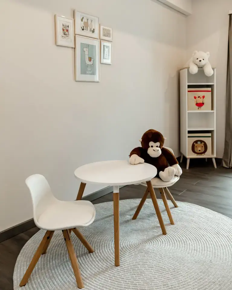 Kindertisch mit zwei weißen Stühlen, ein Stuhl mit großem Plüschaffe, im Hintergrund Regal mit Plüschbär und Tierbildern an der Wand