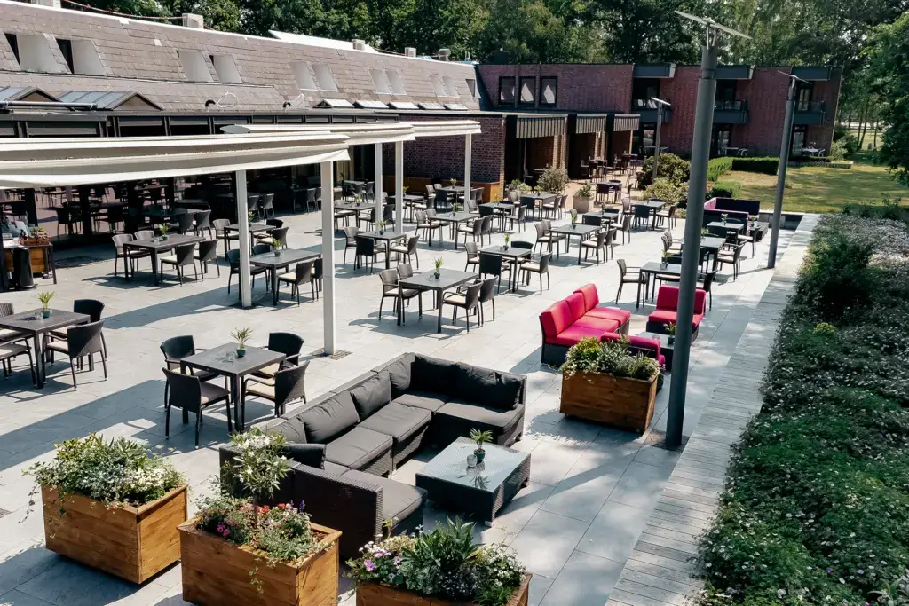 Große Außenterrasse mit Tischen, Stühlen und Sofas vor einem Restaurant am Tankumsee